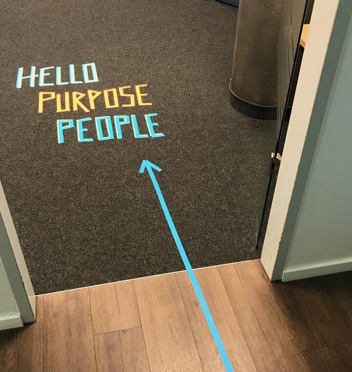 Schriftzug "Hello Purpose People" per Tape auf dem Boden